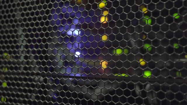 Tracking shot. Colored computer server lights flashing behind rack cabinet door.