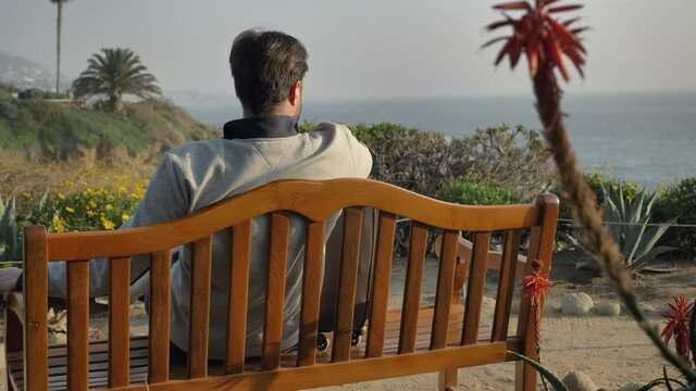 Men sits down on the bench at Laguna Beach admires the view scenic magnificent view