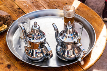 The Moroccan mint tea ceremony, two silver teapots on a tray and three shot glasses