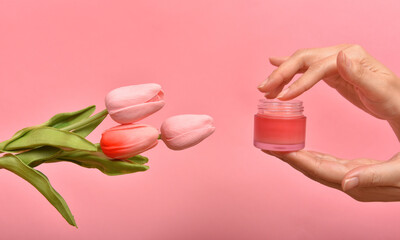 Natural skincare pink bottle, Hand apply cosmetic containers packaging with tulip flower essence extract, Organic beauty product concept.