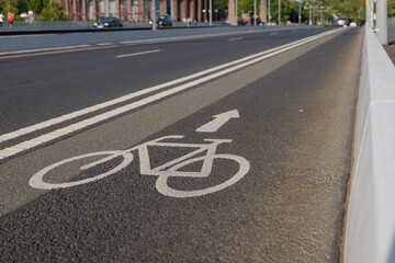 Selected focus view of white bicycle and arrow icon symbol on bicycle lane beside the road on the bridge cross Rhine River in Düsseldorf, Germany. Cycling friendly city concept in Europe. 