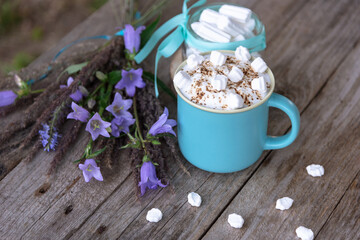 Fototapeta na wymiar Morning coffee with foam and marshmallows on a wooden background with lilac flowers.