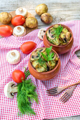 Baked potatoes with mushrooms and various seasonings. in clay pots. Vegetarian.