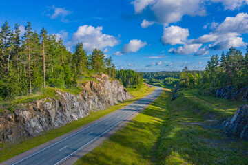 Highway among rocks and pines. Journey. A deserted country road. The highway in the middle of the wilderness. The road goes over the horizon.