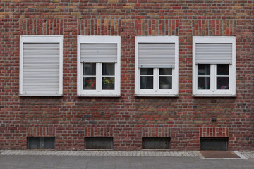 Front exterior street view of typical building, housing or apartment in Europe with white rectangular windows and vintage brick facade.   