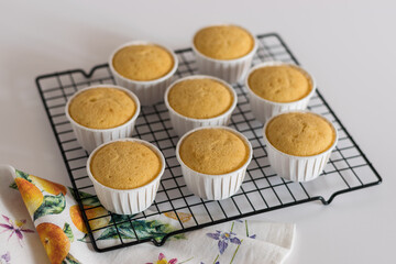 vanilla cupcakes in white cups on a wire rack
