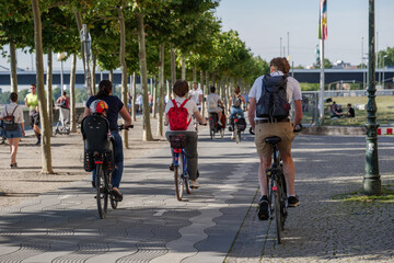 Group of cyclists ride bicycle on bicycle lane on promenade riverside of Rhein River in...