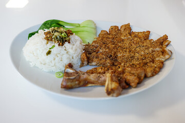 Taiwanese Slice Pork Chop with rice and Pak Choi serve on white plate on white table.  
