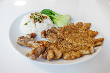 Taiwanese Slice Pork Chop with rice and Pak Choi serve on white plate on white table.  
