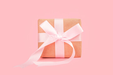 A festive greeting for Christmas or Valentine's Day. Gift box with a beautiful big bow on a pink background.