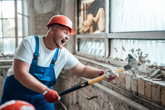 Builder at the construction site, smashing walls with a hammer, screaming
