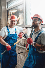 Two tired builders stand on a construction site, taking a break from their work.