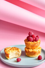 Delicious curd muffin with raspberries on a turquoise platter, on a pink background. Food concept. Copy space for text, hero fancy look, vertical