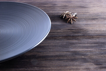 empty black plate on a wooden table and star anise