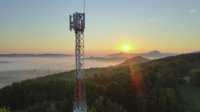 Aerial: European 4G & 5G telecommunication tower on hilltop at sunrise