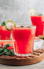 Watermelon lemonade with lime and fresh basil leaves on concrete background. Refreshing summer drink