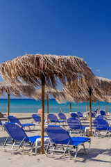 Straw beach umbrellas and sun chairs on the east coast of Zakynthos island in Greece