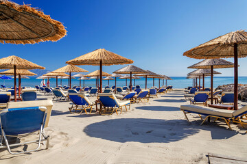 Straw beach umbrellas and sun chairs on the east coast of Zakynthos island in Greece