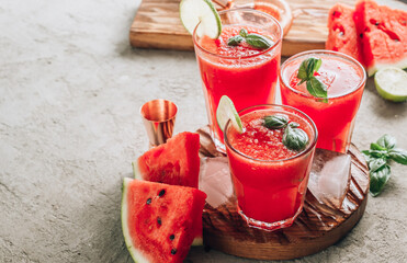 Watermelon lemonade with lime and fresh basil leaves on concrete background. Refreshing summer drink
