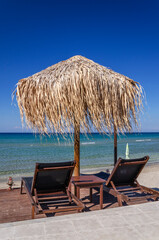 Straw beach umbrellas and sun chairs on the east coast of Zakynthos island in Greece