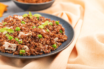 Quinoa porridge with green pea and chicken on ceramic plate on a gray concrete background. Side view, selective focus.