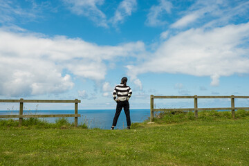 Mujer hispana de mediana edad junto al mar, pensativa mira el horizonte, asturias españa.