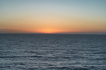 Naklejka premium Sunset in the sea with a mix of orange, yellow and blue tones. Golden hour