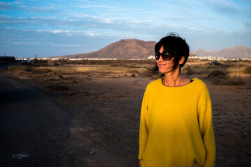 mujer de mediana edad relajada sonriente con gafas de sol al atardecer