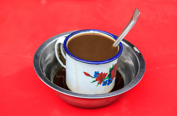 Roadside cooking in Madagascar: coffee with milk in a metal mug.