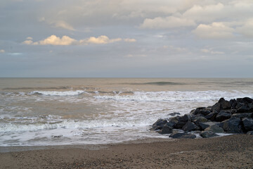 The Irish Sea seascape. Waves, rocks and pebble beach. Evening time, just before sunset.