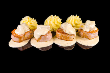 Delicious roasted pork fillets with sauce and parmesan  with reflection, isolated on black background