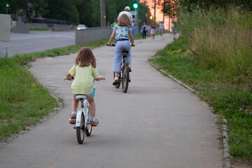 Girls ride a Bicycle on a city street.