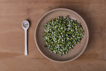Fresh mung bean sprouts in a wooden bowl with wooden spoon on a wooden old backround. Top view. 