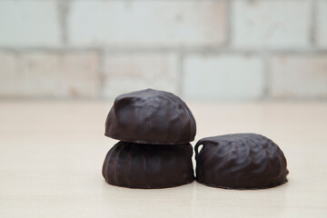 Chocolate-covered marshmallows lie on a wooden table.