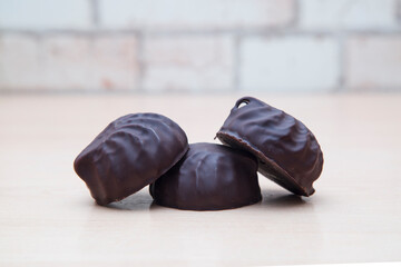 Chocolate-covered marshmallows lie on a wooden table.
