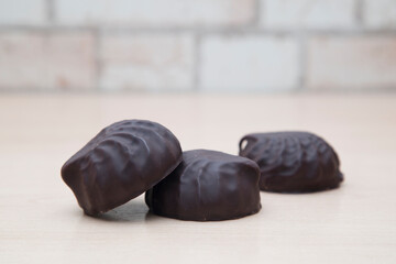 Chocolate-covered marshmallows lie on a wooden table.