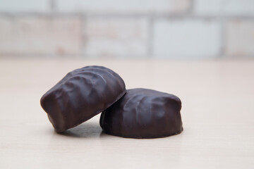 Chocolate-covered marshmallows lie on a wooden table.