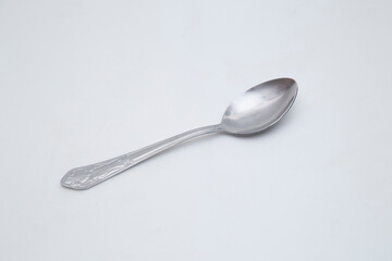 A steel spoon lies on a white background.
