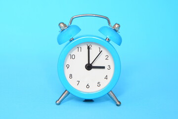 Blue alarm clock on blue background close up. 3 a.m., 3 p.m. Time concept.