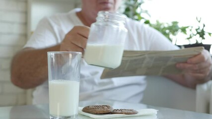 One Person Read a Newspaper and Fill a Glass with Fresh Milk for Breakfast, Enjoying a Tasty and Full with Vitamins Milk