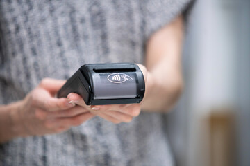 Horizontal view of unrecognizable shop assistant using a credit card terminal as an easy and quick payment method on a shop.