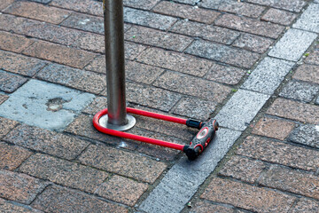 A D lock bike lock locked around a pole on the street