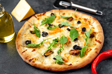 Seafood pizza with salmon, mussels, squid, olives, cheese on a stone background 