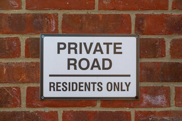 A sign on a brick wall stating Private road residents only