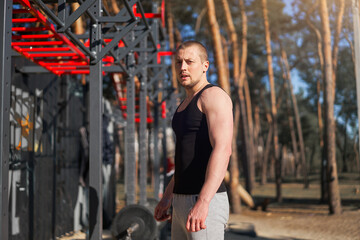 Athletic man standing outdoor gym workout. Handsome caucasian guy cross training nature public gym.