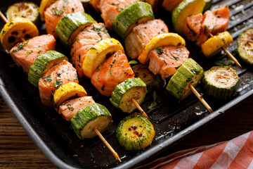 Grilled skewers of salmon with zucchini in a herb marinade in a grill pan close up view