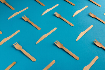 Wooden eco friendly forks and knives pattern on blue background