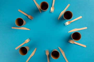 Wooden disposable cutlery set arranged in border frame on colorful background with copy space