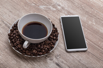 Fototapeta na wymiar coffee cup with coffee beans inside the plate and a phone on a wooden desk for an office