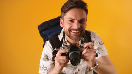 Portrait shot of young caucasian bearded traveler smiling with backpack and camera. High quality photo